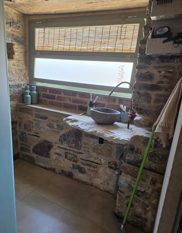 Bathroom with a stone basin on a stone shelf under the window