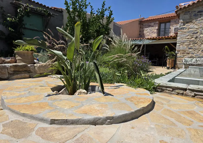Round flagstone courtyard with ornamental grasses and a strelitzia
