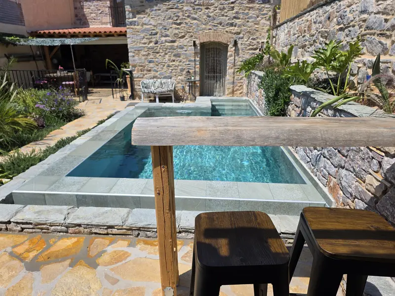 The pool seen from the outdoor bar, with stools at a wooden counter
